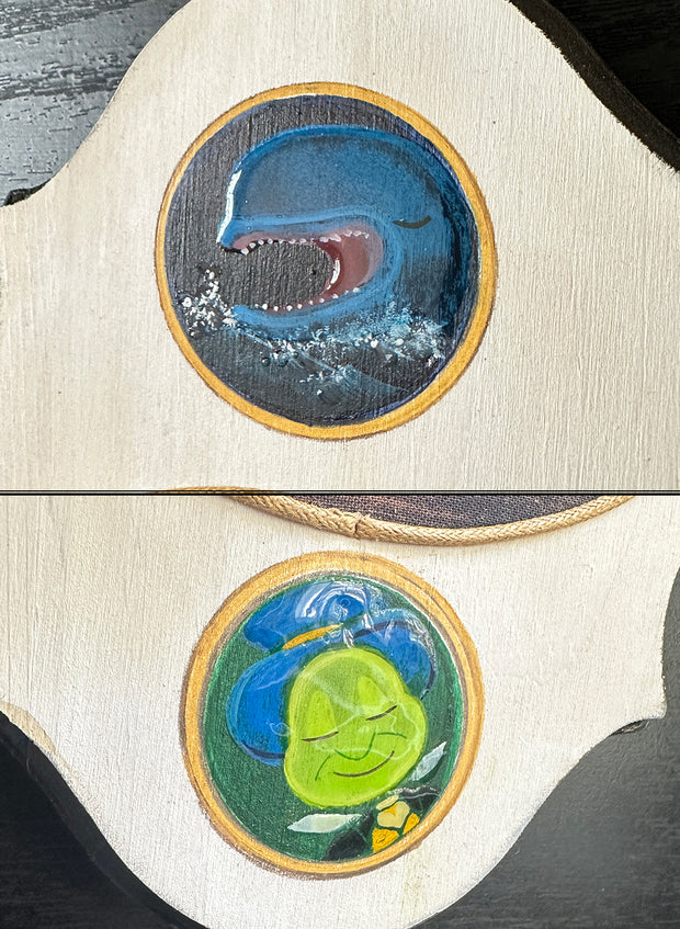 Close up of 2 painted details on the plaque: a large opened mouth whale and Jiminy Cricket.