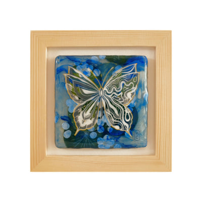 Painting of a white butterfly with a background of green and blue abstract imagery, to make the piece look like a collage. Piece is framed in wooden frame.