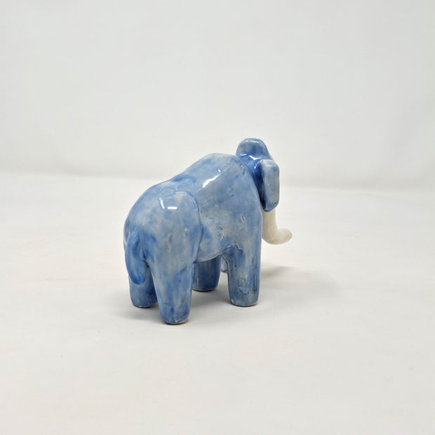 Ceramic sculpture of a blue mammoth, with large curved tusks and a long nose that touches the ground.