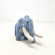 Ceramic sculpture of a blue mammoth, with large curved tusks and a long nose that touches the ground.