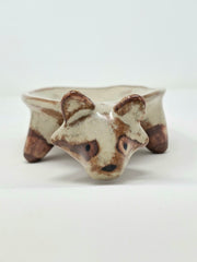 Ceramic vessel like a shallow plate with 4 legs and a raccoon head at the front of the plate.