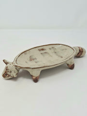 Ceramic vessel like a shallow plate with 4 legs and a raccoon head at the front of the plate.