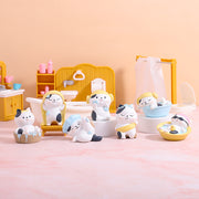 Several small figurines of white cats with black spots, bathing or in various positions to indicate they've just bathed such as toweling off, scrubbing bubbles or sitting in a tub.