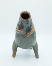 Glazed ceramic sculpture of a large rounded body monster, standing on hind legs with many small teeth and an open mouth. Colors are blue with brown accent coloring.