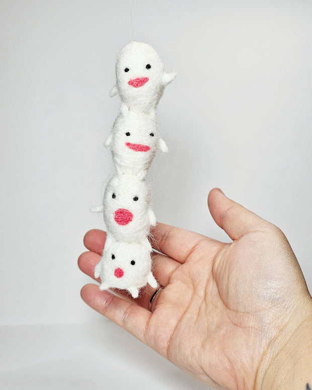 Needle felted sculpture of a stack of 4 cute, simplistic white blob characters with tiny limbs and pink mouthed smiles. They stand in various poses.