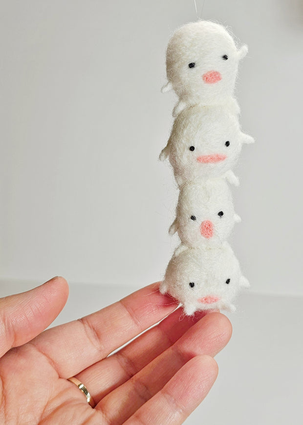 Needle felted sculpture of a stack of 4 cute, simplistic white blob characters with tiny limbs and pink mouthed smiles. They stand in various poses.