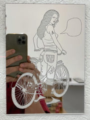 Stencil cut out of a mirrored surface of a girl standing over a bike, as if pausing from riding. She looks back over her shoulder and has an empty speech bubble.