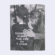 Back cover of zine, a black and white photo of Barry hugging someone with a shirt with Old English font on the back.