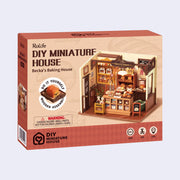 Product packaging for a DIY Miniature House of a bakery, filled with various baked goods and baking utensils. Modeled like a bakery store front.