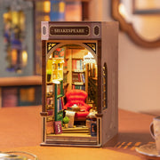 3D Booknook of a Shakespeare bookstore, with a big red arm chair and many rows of books around and behind. Contained within a rectangle that goes on a bookcase.