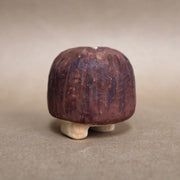 Small mushroom sculpture whittled out of wood, designed like a shiitake with small cartoon eyes and tiny feet.