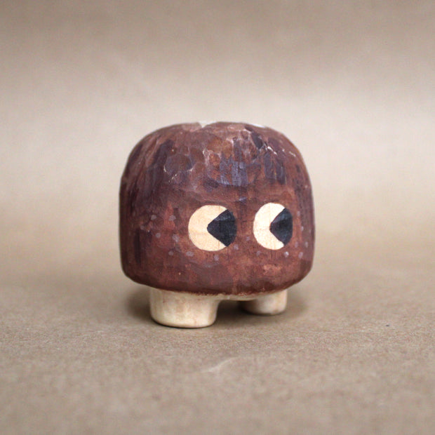 Small mushroom sculpture whittled out of wood, designed like a shiitake with small cartoon eyes and tiny feet.