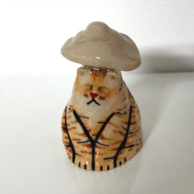 Ceramic sculpture of an orange cartoon style tiger, sitting. A light tan colored cloud looms over its head.