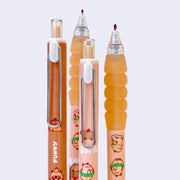 Collection of several gel pens with brown bodies, a rounded metal clip and a squishy barreled surface for placing one's hand. Small illustrations of cartoon capybaras are on the pens and product packaging.