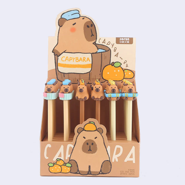 Display of 36 pens, tan and light yellow with rubber capybara shaped characters as pen toppers.