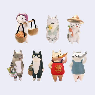 7 vinyl figurines of small cats with various accessories themed around market shopping, such as bags or produce or fish.