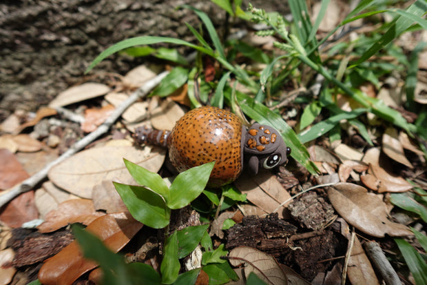 Small ceramics sculpture of a brown Ankylosaurus, with large cute eyes and a dotted outer shell. 