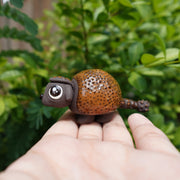 Small ceramics sculpture of a brown Ankylosaurus, with large cute eyes and a dotted outer shell. 