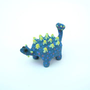 Sculpture of a blue stylized Ankylosaurus with neon green spikes and blue and purple polka dots on its body. It has a long tail and large shiny eyes.