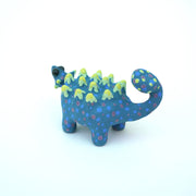 Sculpture of a blue stylized Ankylosaurus with neon green spikes and blue and purple polka dots on its body. It has a long tail and large shiny eyes.