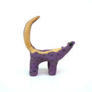 Ceramic sculpture of a purple skunk, done in a cartoon style with large bulbous black eyes and a very small, skinny head.