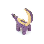 Ceramic sculpture of a purple skunk, done in a cartoon style with large bulbous black eyes and a very small, skinny head.