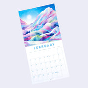 Staple bound calendar for the month of February, with one page being a full bleed illustration and the other having space for writing in each day. Illustration is of a snowy but very colorful mountain scene with waterfalls. 