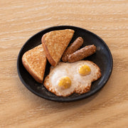 Small assembled clay sculpture of a breakfast on a plate of eggs, toast and 2 links of sausage. 