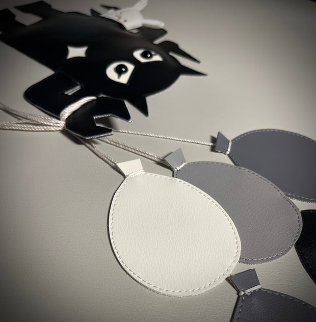 Greyscale pleather fabric art wrapped around a panel of a Big Boss Robot holding a bouquet of balloons in one hand and a small white bunny under the other arm.