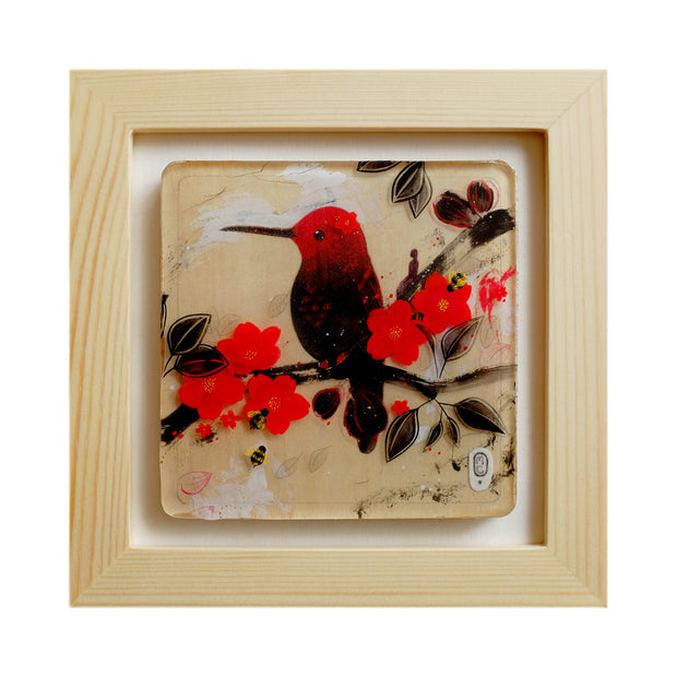 Illustration of a black and red hummingbird sitting on a branch with red flower blossoms and black leaves. A small silhouetted woman sits on the branch and looks onwards. Piece in open frame.