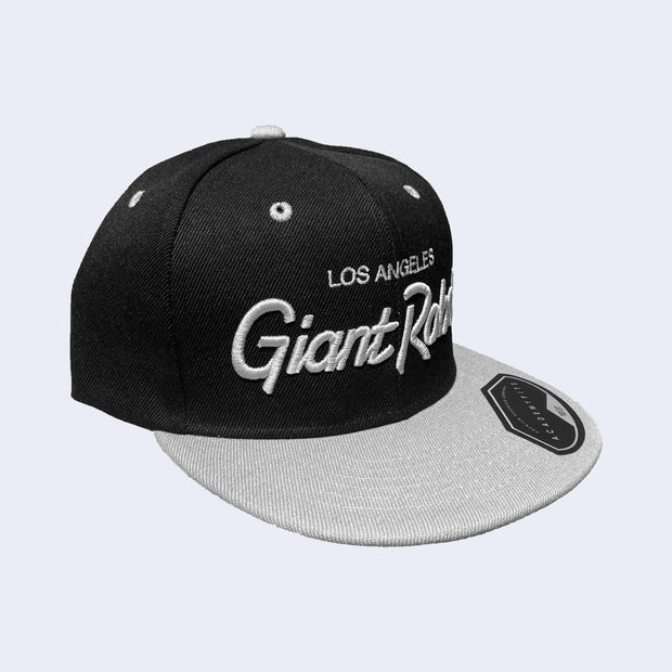 Flat billed black cap with a gray bill and gray stylized letters that say "Los Angeles Giant Robot" across the front.