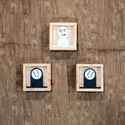 3 small wooden boxes with light fixtures in the back illuminating the cut out character in the center. One is a Kodama, two are No Face.