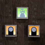 3 small wooden boxes with light fixtures in the back illuminating the cut out character in the center. One is a Kodama, two are No Face.