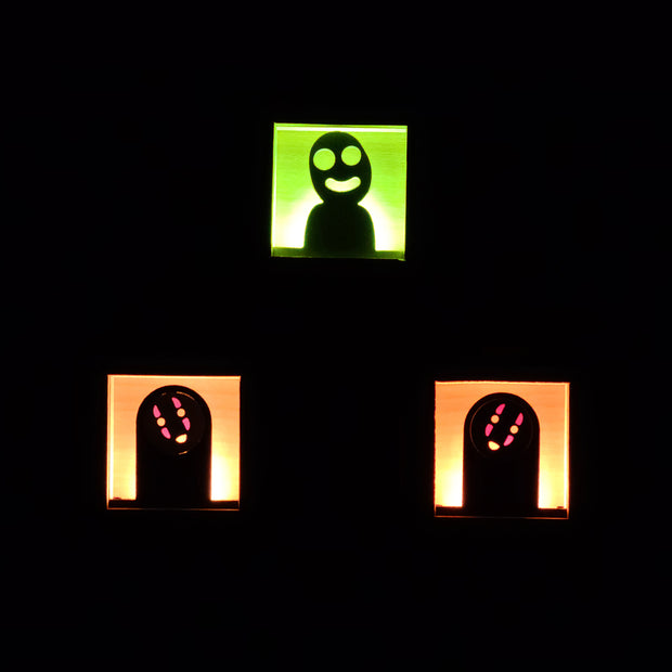 3 small wooden boxes with light fixtures in the back illuminating the cut out character in the center. One is a Kodama, two are No Face.