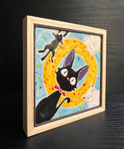 Ceramic tile light blue with a yellow circle. Each corner has a cat character: Jiji from Kiki's Delivery Service, the white cat from Kiki's Delivery Service and their kittens.