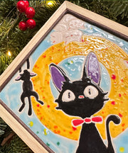 Ceramic tile light blue with a yellow circle. Each corner has a cat character: Jiji from Kiki's Delivery Service, the white cat from Kiki's Delivery Service and their kittens.