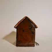 Back view of ceramic sculpture of a brown dog house.