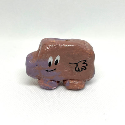 Clay sculpture of a simplistic car with painted on cartoon eyes and a single hand.