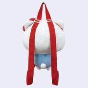 Plush doll of Hello Kitty, with her iconic red bow and blue overalls, made into a backpack with red straps and a zip atop the back of her head. Back view.