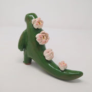 Glazed ceramic sculpture of a green Godzilla figure with lotus flower instead of back spikes. It reaches one hand out.