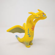 Sculpture of King Ghidorah, with 3 long necks and a set of small wings. It is painted yellow with a floral motif on its stomach. Each face has a different expression.