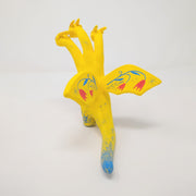 Sculpture of King Ghidorah, with 3 long necks and a set of small wings. It is painted yellow with a floral motif on its stomach. Each face has a different expression.