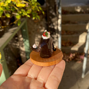 Small sculpture of a snake shaped like a chocolate swiss roll with strawberry cream filling. The snake's head comes out of the cake swirl and has a dollop of whipped cream. Atop the snake's back is a larger dollop of whipped cream with strawberries.