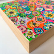 Colorful collage style painting of many brightly colored flowers on round stickers all pasted atop one another.