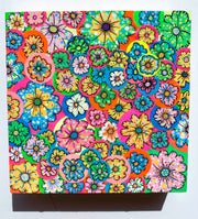 Colorful collage style painting of many brightly colored flowers on round stickers all pasted atop one another.