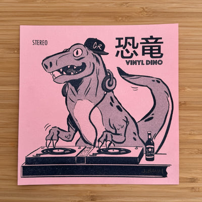 Risograph print on pink paper of a dinosaur wearing a GR hat, headphones and mixing at a DJ table. Nearby it has Japanese and English text which reads "Vinyl Dino"