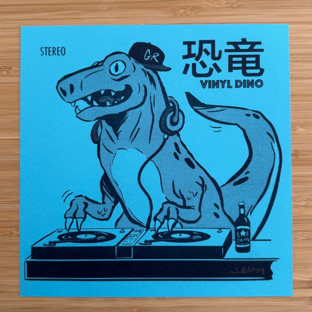 Risograph print on blue paper of a dinosaur wearing a GR hat, headphones and mixing at a DJ table. Nearby it has Japanese and English text which reads "Vinyl Dino"