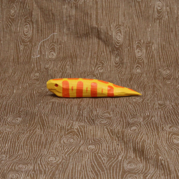 Wooden sculpture of a short and fat yellow snake with orange stripes and a red eye. Its body is akin to a banana slug.