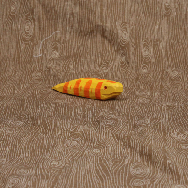 Wooden sculpture of a short and fat yellow snake with orange stripes and a red eye. Its body is akin to a banana slug.