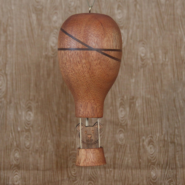 Wooden sculpture of a hot air ballon with a small bear sitting in the basket. 